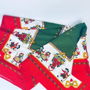 Può includere: Tovaglia rossa, bianca e verde con un design di arte popolare con figure danzanti e cuori. La tovaglia ha un pannello centrale verde e bordi rossi.