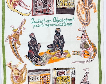 May include: A white linen tea towel with a green border featuring illustrations of Australian animals and Aboriginal art. Text includes "GREETINGS FROM CANBERRA", "Australian Aboriginal paintings and carvings", "DESIGNED IN AUSTRALIA", and "ALL PURE LINEN".