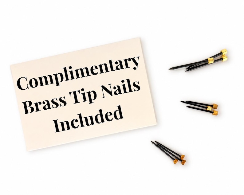 May include: A cream-colored card with the text "Complimentary Brass Tip Nails Included" next to three black nails with gold-colored tips. The nails are arranged on a white background.