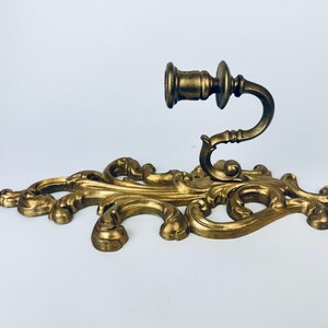 以下が含まれることがあります： 金色の装飾的な壁掛け燭台。燭台は、キャンドルカップを保持する湾曲したアームを備えた、装飾的なスクロールデザインが特徴です。 全体的なスタイルはヴィンテージでエレガントです。
