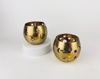 以下が含まれることがあります： カットアウトデザインの金色の金属製キャンドルホルダー2つ。1つのホルダーは月と星のデザイン、もう1つは花のデザインです。