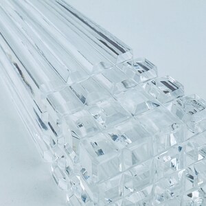 May include: Close-up of a clear, faceted glass object. The object has a geometric design with rectangular and square shapes. The glass is transparent, reflecting light and creating a sparkling effect. The overall theme is decorative.