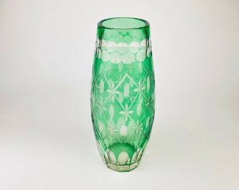 May include: A green glass vase with a cut glass design. The vase has a rounded body and a flared top.