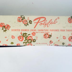 May include: A rectangular box of Polyfab scented drawer lining. The box is cream-colored with a floral pattern of pink roses and green leaves. The text "Polyfab" is in a stylized script, with the words "Scented Drawer Lining" below.