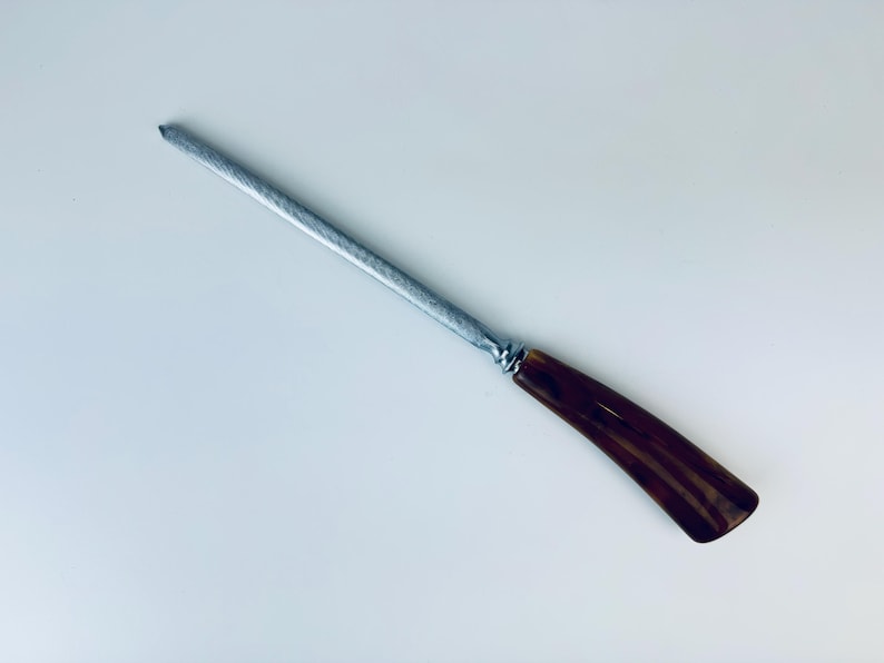 May include: A silver steel knife sharpener with a brown and black striped plastic handle.