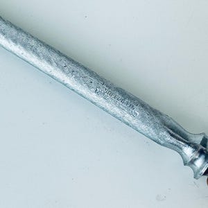 May include: A silver steel knife sharpener with a wooden handle. The sharpener has a textured surface and the words "W&uuml;sthof Trident" are engraved on the side.