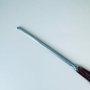 May include: A silver metal knife sharpener with a brown wooden handle.
