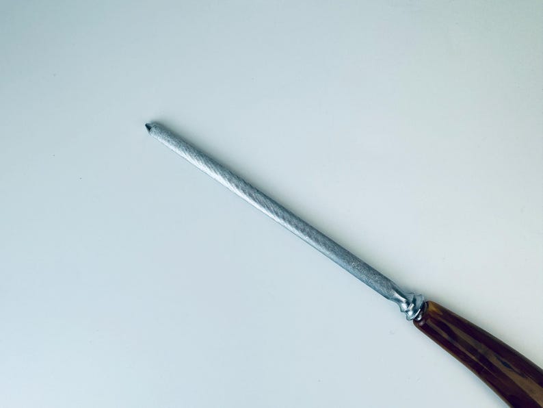 May include: A silver metal knife sharpener with a brown wooden handle.