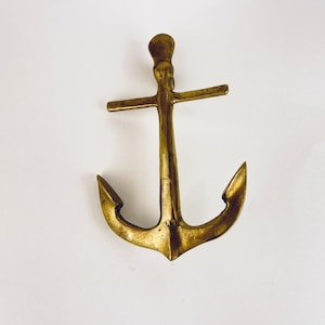 May include: A gold-toned metal anchor with a crossbar. The anchor is a decorative item and is not intended for use in water.