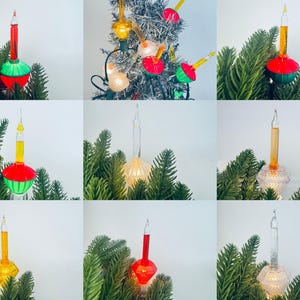 以下が含まれることがあります： 赤、黄色、透明など、さまざまな色のヴィンテージクリスマスツリーライトのコレクション。ライトはクラシックなバブル型で、緑の松の枝を背景に表示されています。ライトは懐かしい休日の装飾です。