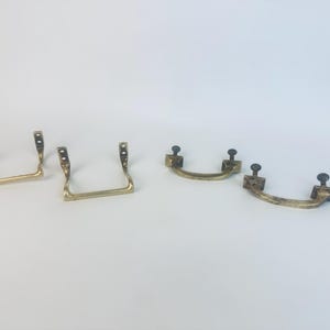 Puede incluir: Cuatro tiradores de cajón de latón vintage. Dos tienen forma de U con orificios de montaje, y dos son curvos con postes atornillables. El latón tiene una pátina cálida y envejecida, lo que sugiere que son antiguos o vintage.