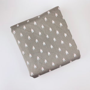 May include: A gray fabric with a white and light pink repeating pattern of small houses.