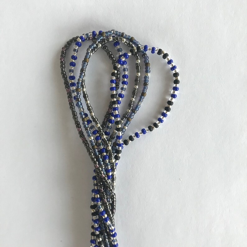 May include: A close-up of a beaded necklace with multiple strands of blue, black, silver, and gray beads.