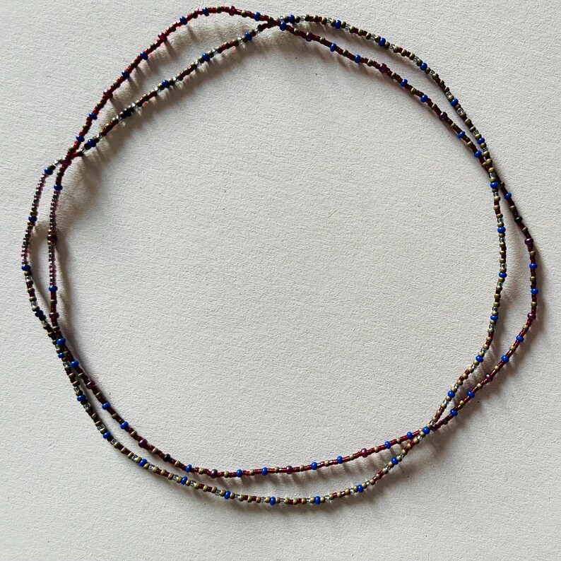 Puede incluir: Un collar de cuentas de doble cadena con cuentas alternas de plata, rojo y azul.