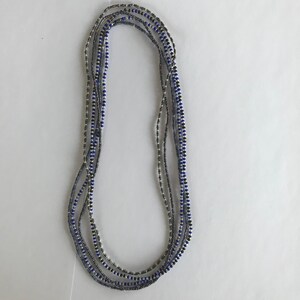 May include: A multi-strand necklace made of silver and blue beads. The necklace is layered and has a simple design.