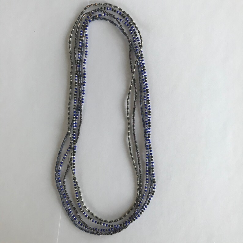 May include: A multi-strand necklace made of silver and blue beads. The necklace is layered and has a simple design.