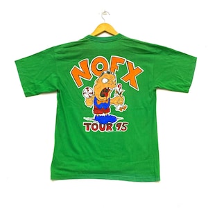 Puede incluir: Camiseta verde de manga corta con un personaje de dibujos animados y el texto "NOFX TOUR 95" impreso en la espalda.