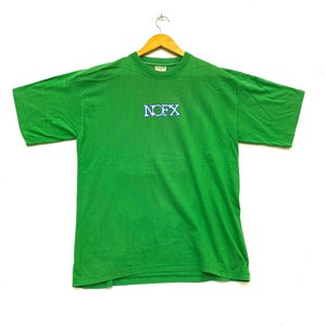 Puede incluir: Camiseta verde de manga corta con un logotipo "NOFX" azul y blanco en la parte delantera.