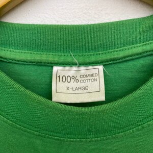 Puede incluir: Camiseta verde con una etiqueta blanca que dice "100% algod&oacute;n peinado X-Large"