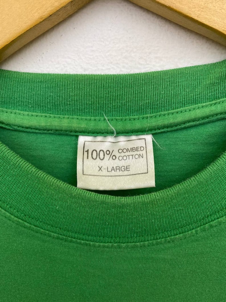 Puede incluir: Camiseta verde con una etiqueta blanca que dice "100% algod&oacute;n peinado X-Large"