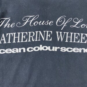 Puede incluir: Camiseta negra con texto blanco que dice "The House of Love Catherine Wheel ocean colour scene"