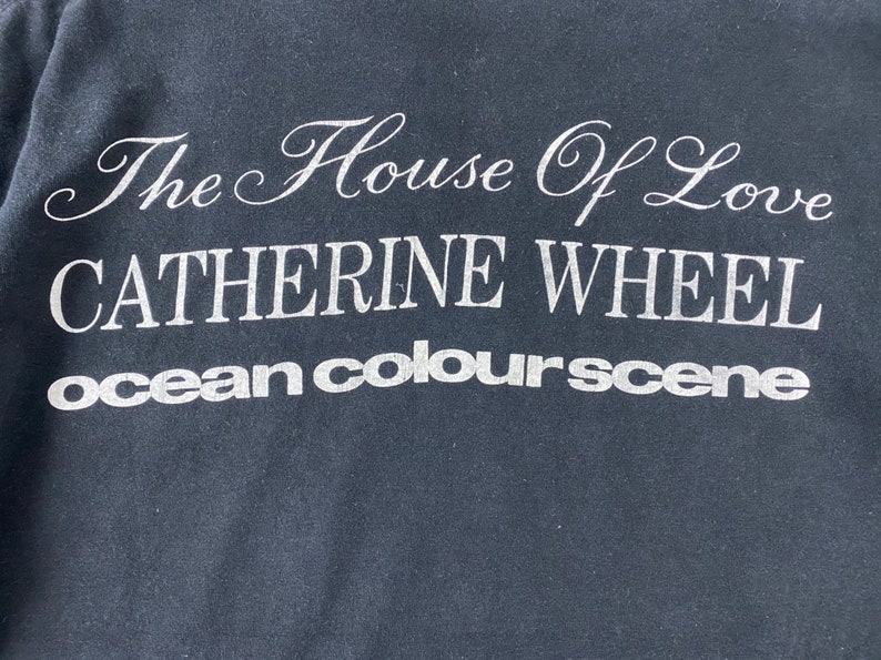 Puede incluir: Camiseta negra con texto blanco que dice "The House of Love Catherine Wheel ocean colour scene"
