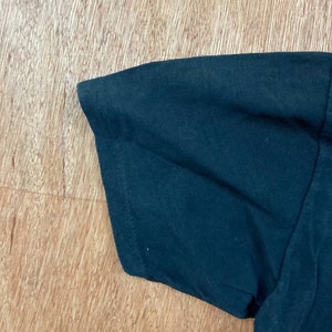Puede incluir: Primer plano de la manga azul oscuro de una camiseta. La tela es lisa y parece ser de algod&oacute;n.