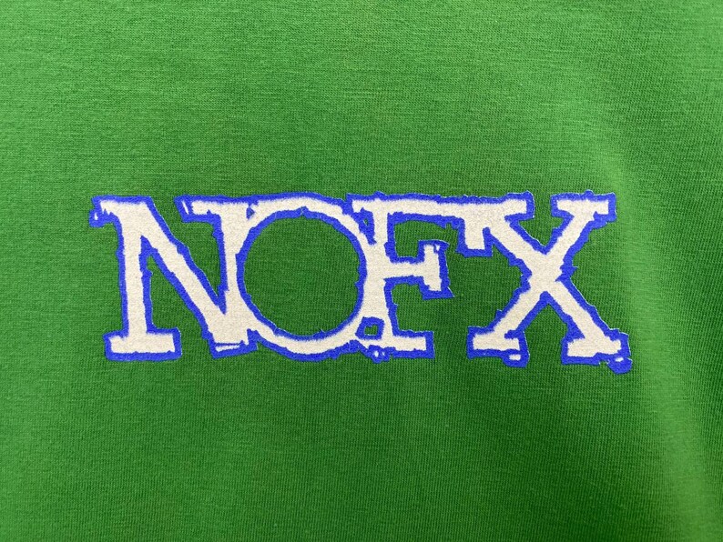 Puede incluir: Una camiseta verde con un logotipo "NOFX" blanco en un contorno azul.