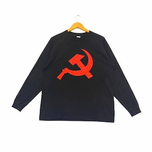 May include: Black long-sleeve shirt featuring a large red hammer and sickle graphic on the front. The shirt is hanging on a wooden hanger against a white background. The graphic is a bold, solid color.