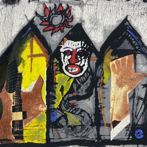 Puede incluir: Una camiseta negra y blanca con un dise&ntilde;o gr&aacute;fico abstracto de colores. El dise&ntilde;o presenta una cara con la nariz y la boca rojas, una guitarra y una mano que se levanta. El dise&ntilde;o est&aacute; rodeado de un fondo negro y blanco.