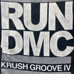 K&ouml;nnte beinhalten: Schwarzes T-Shirt mit einem wei&szlig;en Aufdruck der W&ouml;rter "RUN DMC" und "KRUSH GROOVE IV".