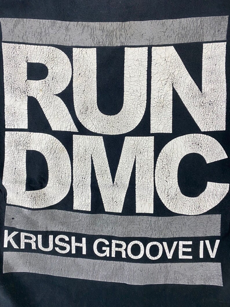 K&ouml;nnte beinhalten: Schwarzes T-Shirt mit einem wei&szlig;en Aufdruck der W&ouml;rter "RUN DMC" und "KRUSH GROOVE IV".