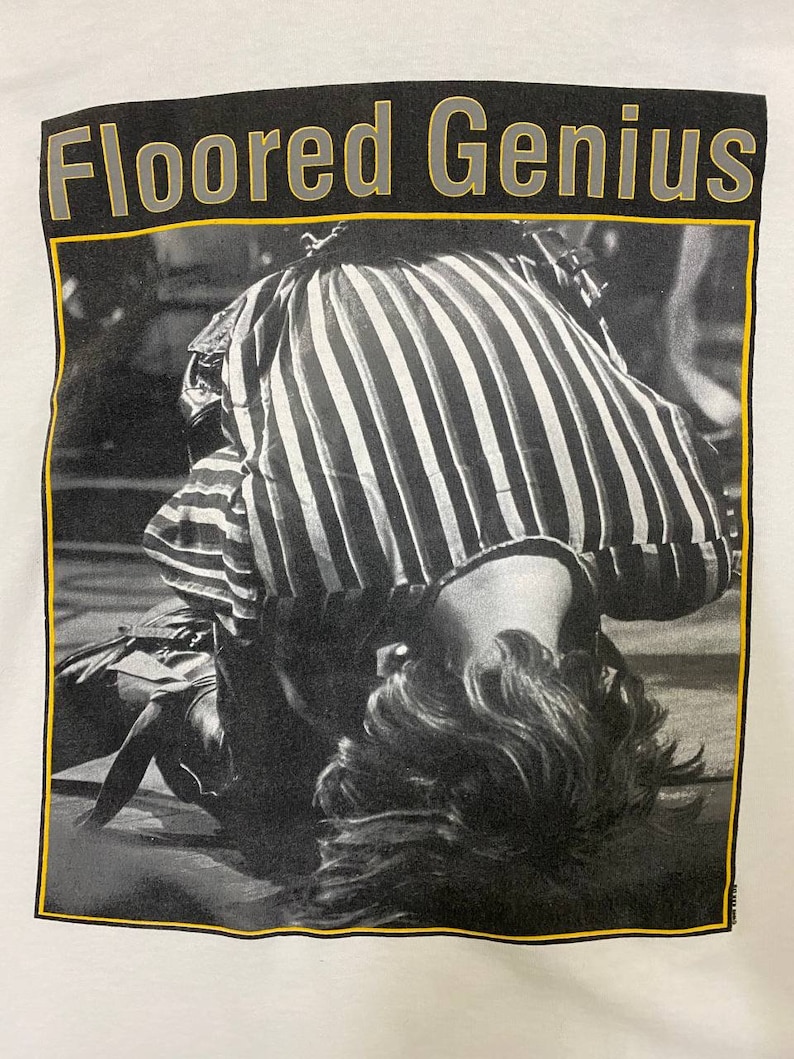 Pu&ograve; includere: Foto in bianco e nero di una persona sdraiata sulla schiena con la testa rivolta verso la fotocamera. La persona indossa una camicia a righe e ha i capelli che le coprono il viso. La foto &egrave; incorniciata da un bordo nero e giallo con il testo "Floored Genius" sopra la foto.