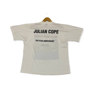 Pu&ograve; includere: Maglietta bianca con testo nero che recita "JULIAN COPE ESCAPE FROM BALFE TEN YEAR ANNIVERSARY 1992 CE."