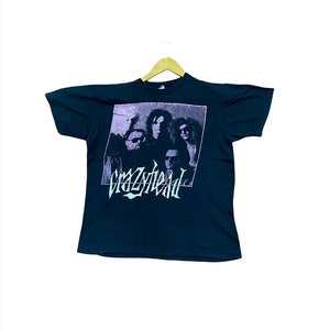 Puede incluir: Camiseta negra con un gr&aacute;fico de banda de "Crazyhead" en un esquema de color morado y turquesa. El gr&aacute;fico presenta una banda de cuatro personas en blanco y negro.
