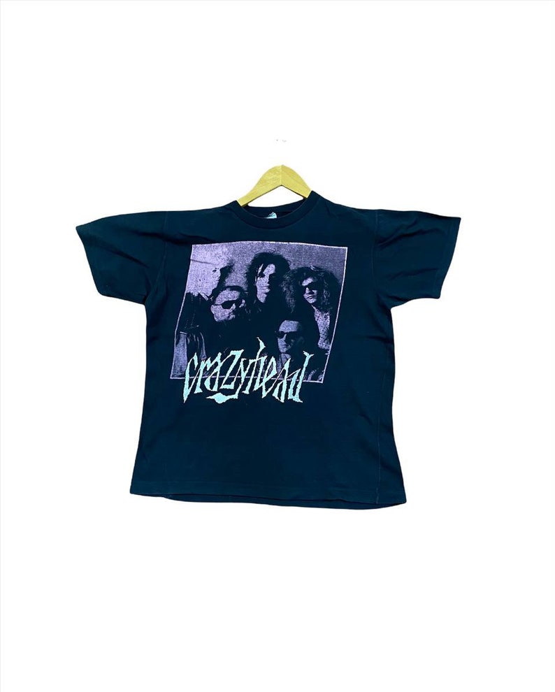 Puede incluir: Camiseta negra con un gr&aacute;fico de banda de "Crazyhead" en un esquema de color morado y turquesa. El gr&aacute;fico presenta una banda de cuatro personas en blanco y negro.