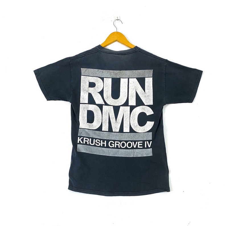 K&ouml;nnte beinhalten: Schwarzes T-Shirt mit einem wei&szlig;en Grafikdruck von "RUN DMC" und "KRUSH GROOVE IV" auf der R&uuml;ckseite.