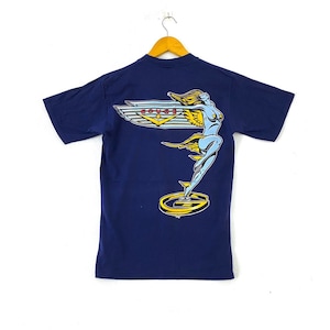 Puede incluir: Una camiseta azul marino con un estampado gráfico de una mujer alada de pie sobre una plataforma circular con la palabra "COVER" en letras rojas.