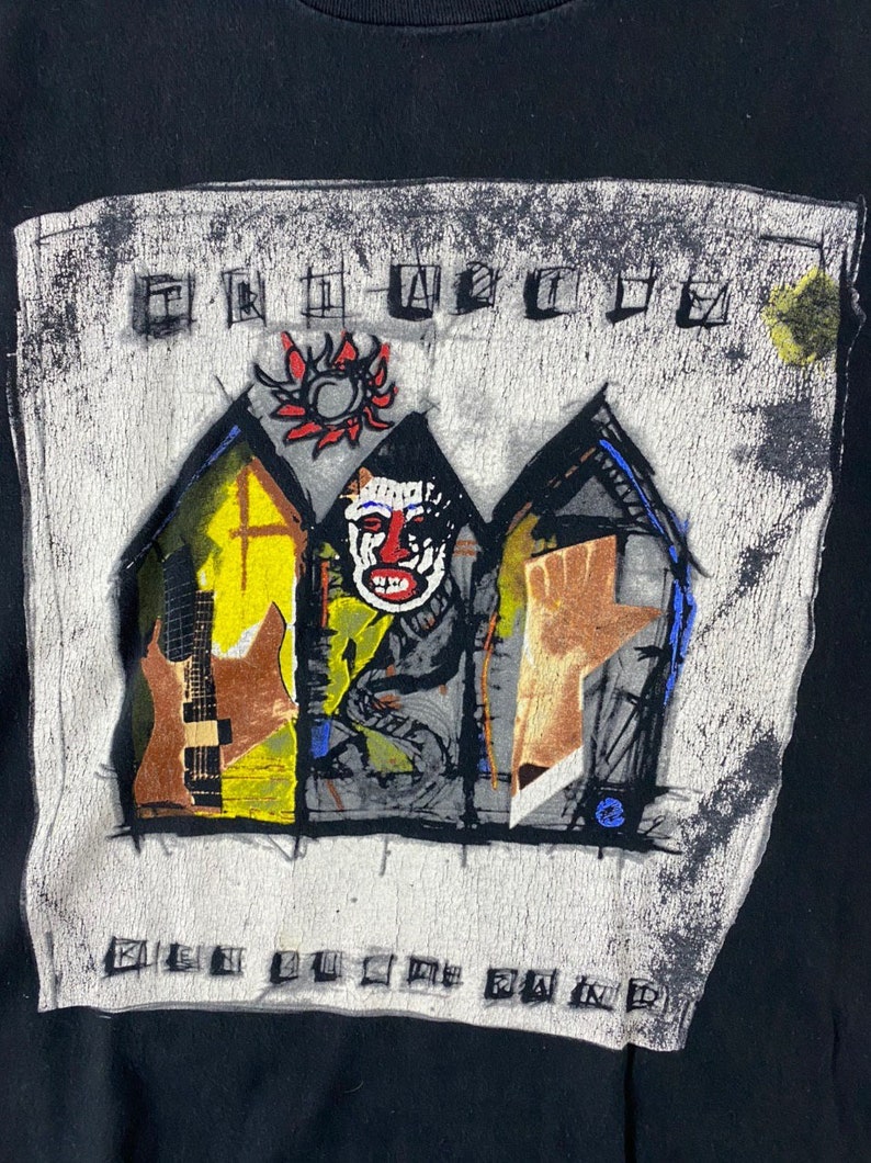 Puede incluir: Camiseta negra con un estampado gr&aacute;fico blanco de una imagen estilizada de tres casas con un sol rojo, una cara y una mano. El texto "The Offspring" y "Smash" est&aacute; impreso en la camiseta.