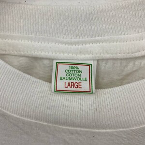 May include: White t-shirt with a green and white tag that reads "100% Cotton Coton Baumwolle Large"