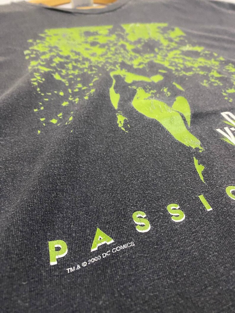 May include: A black t-shirt with a green graphic print of a face and the text "PASSION" in green letters. The text "TM & &copy; 2000 DC COMICS" is printed in white below the graphic.