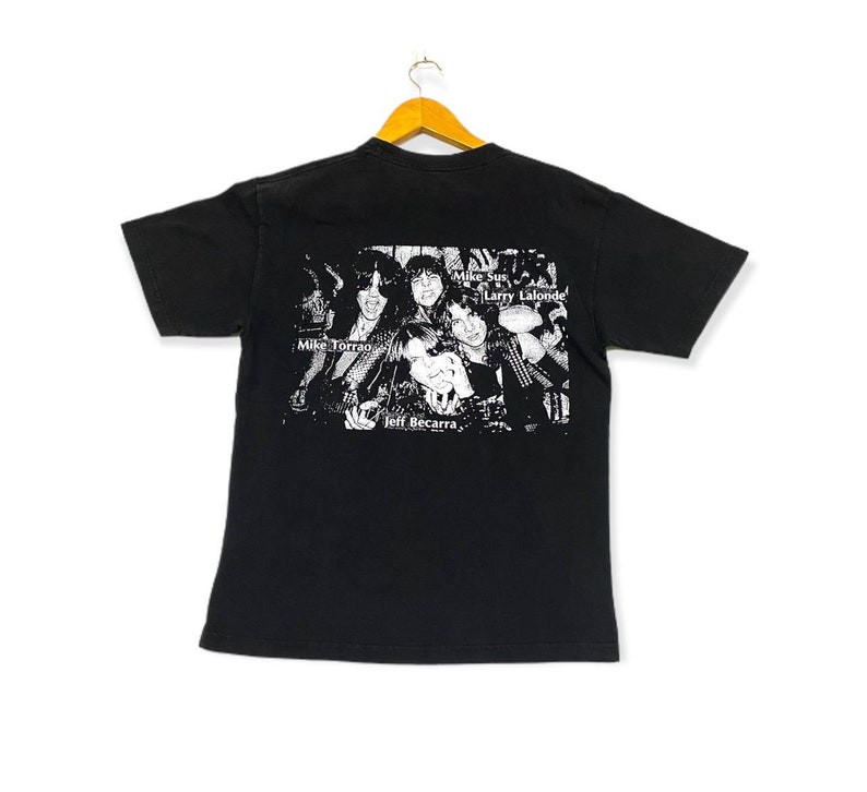 May include: Black t-shirt with a white print of a band. The band members are Mike Torrao, Jeff Becarra, Mike Starr, and Larry Lalonde. The band's name is not visible.