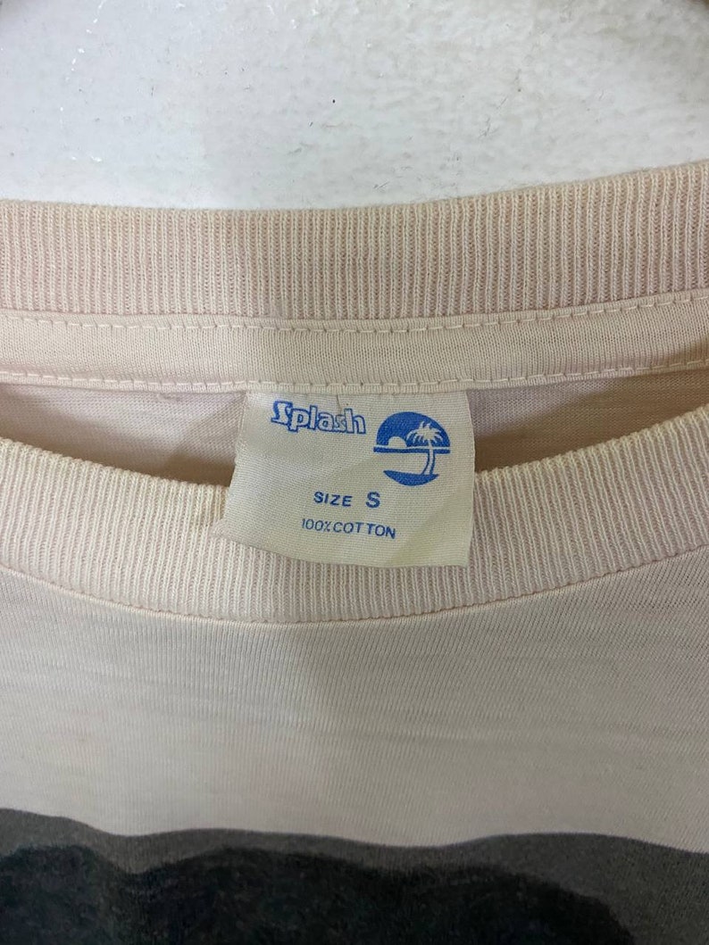 Puede incluir: Una camiseta rosa claro con una etiqueta azul y blanca que dice "Splash" y "Talla S 100% Algod&oacute;n".