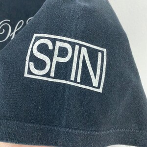 Puede incluir: Camiseta negra con texto blanco que dice "SPIN" en un cuadro.