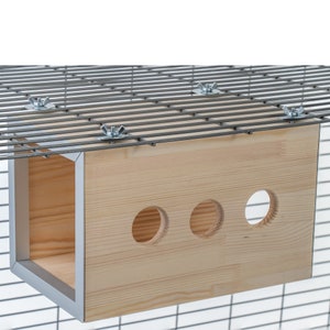 May include: A wooden hanging house for small pets, with three round openings and a light wood finish. The house is attached to a wire cage with metal nuts and bolts.