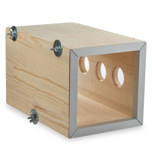 May include: A wooden box with a grey trim and four holes on one side. The box has metal fasteners on each corner.
