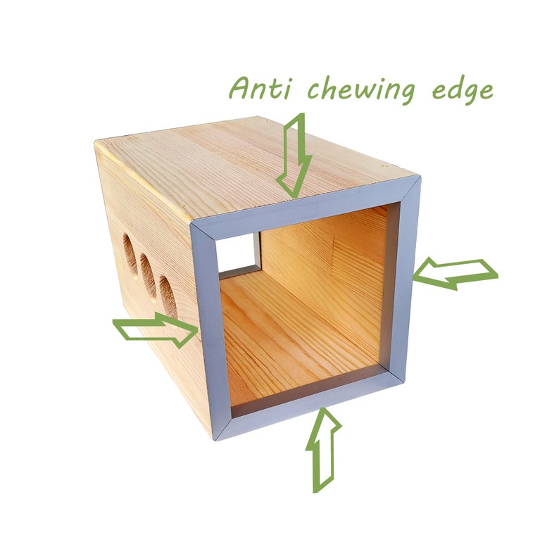 May include: A wooden box with a grey rubber edge around the opening. The box has several holes on the side and the text "Anti chewing edge" is written above the box.