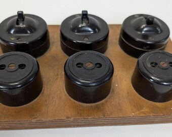Vintage bakeliet, 3 dolly-tuimelschakelaars en 3 tweepolige stopcontacten op houten sokkel
