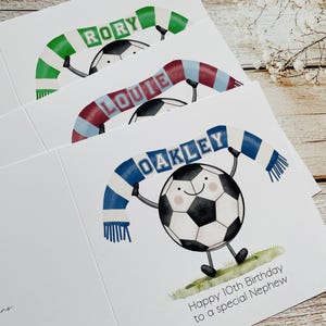 Puede incluir: Tarjetas de felicitaci&oacute;n con personajes de balones de f&uacute;tbol de dibujos animados que llevan bufandas. Las bufandas son de varios colores y tienen nombres. Una tarjeta tiene el mensaje "Happy 10th Birthday to a special Nephew" en la parte inferior.