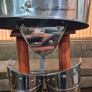 May include: A silver metal suit of armor with a helmet, breastplate, and leg armor. The armor is displayed on a wooden stand with two wooden posts. The armor is polished and shiny.